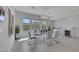 Modern dining area featuring a glass table, white chairs, and gray cabinetry at 3005 Merlesco Ave, Henderson, NV 89044