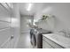 Well-lit laundry room featuring modern washer and dryer, sink, white cabinets, and window at 3005 Merlesco Ave, Henderson, NV 89044