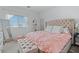 Inviting bedroom featuring a tufted headboard, soft pink bedding, and a cozy seating area by the window at 3729 Canis Minor Ln # 10206, Henderson, NV 89052