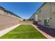 A backyard featuring artificial turf, brick-paved patio, and a sliding glass door leading inside at 4633 Fragrant St, North Las Vegas, NV 89031