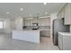 Open kitchen with stainless steel refrigerator, an island, gray cabinets, and tile flooring at 4633 Fragrant St, North Las Vegas, NV 89031