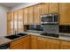 Close up of a kitchen with wood cabinets, stainless steel appliances, and granite countertops at 5017 Kaibab Forest Ave, Las Vegas, NV 89141