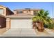 Two-story home featuring a two car garage, desert landscaping, and a palm tree at 5456 Raccoon Valley Ln, Las Vegas, NV 89122