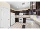 Traditional kitchen with white appliances, dark wood cabinetry, and granite countertops at 5456 Raccoon Valley Ln, Las Vegas, NV 89122