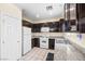 Functional kitchen with white appliances, granite countertops, and dark wood cabinetry at 5456 Raccoon Valley Ln, Las Vegas, NV 89122