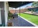 Landscaped backyard with artificial grass, paved patio with outdoor seating, and decorative plantings against a brick wall at 5733 Coral Sun St, North Las Vegas, NV 89031