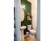 Stylish powder room features a pedestal sink, oval mirror, and a toilet with a bold green accent wall at 5733 Coral Sun St, North Las Vegas, NV 89031