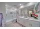Bright bathroom featuring double sinks, sleek white cabinetry, and a glass-enclosed shower with modern fixtures at 6490 Wagon Wheel Ct, Pahrump, NV 89061