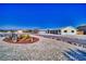 This desert home features gravel yards and a circular drive with desert landscaping in the front at 6490 Wagon Wheel Ct, Pahrump, NV 89061
