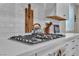 Close-up of a modern gas stovetop with white countertops and subway tile backsplash at 741 Monroe Hill Pl, Henderson, NV 89011