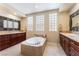 Luxurious bathroom featuring dual sinks, a soaking tub, and natural light at 7567 Desertscape Ave, Las Vegas, NV 89178