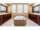 Luxurious bathroom featuring dual sinks, a soaking tub, and natural light at 7567 Desertscape Ave, Las Vegas, NV 89178