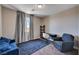 Cozy bedroom setup with a large blue couch, chair, desk, and natural light at 7572 Mount Spokane Ct, Las Vegas, NV 89113