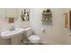 Bright bathroom featuring a pedestal sink, toilet, and stylish shelving with decorative towels and plants at 8 Laricola Ct, Henderson, NV 89011