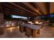 Outdoor kitchen and fireplace at night with mountain views and outdoor seating area at 8 Laricola Ct, Henderson, NV 89011
