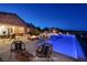 Swimming pool and spa at night with seating area, fireplace, and covered patio in the background at 8 Laricola Ct, Henderson, NV 89011