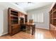 Home office with custom built-in wood bookshelves, cabinets, desk, and hardwood floors at 8205 Taos Paseo Ave, Las Vegas, NV 89128