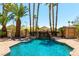 Sparkling pool and waterfall surrounded by tropical palm trees creates a backyard oasis at 8205 Taos Paseo Ave, Las Vegas, NV 89128