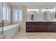 Bright bathroom with a modern tub, tiled floor, and vanity with double sinks and dark wood cabinets at 8437 Apple Hill Ct, Las Vegas, NV 89128