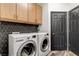 Modern laundry room with black tiled backsplash, cabinets, and front load washer and dryer at 8713 Castle Ridge Ave, Las Vegas, NV 89129