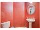 Elegant powder room with pedestal sink, round mirror and red accent wall at 9303 Gilcrease Ave # 1056, Las Vegas, NV 89149