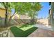Lush backyard featuring artificial turf, desert landscaping, a patio, and mature trees at 9452 Plover Falls Ave, Las Vegas, NV 89149