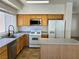 Clean kitchen with white appliances, oak cabinets, an island, and ample natural light from the window at 9452 Plover Falls Ave, Las Vegas, NV 89149