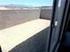 View of the dirt backyard, framed by sliding glass doors and a block wall, showcasing outdoor potential at 10400 Luna Mezzo St Ave # Lot 193, Las Vegas, NV 89141