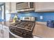 Close-up of stainless steel gas cooktop and oven surrounded by countertops and white cabinets at 10400 Luna Mezzo St Ave # Lot 193, Las Vegas, NV 89141
