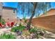 Landscaped backyard featuring a brick fence and shady seating beneath a leafy tree canopy at 10692 Tulip Valley Rd, Las Vegas, NV 89179