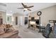 Bonus room with seating area and built-in desk featuring dark brown sofa, guitar case, and ceiling fan at 10692 Tulip Valley Rd, Las Vegas, NV 89179
