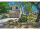Charming two-story home with a well-manicured front yard, lush trees, and a spacious driveway leading to a two-car garage at 10692 Tulip Valley Rd, Las Vegas, NV 89179