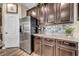 Close-up of kitchen area with stainless steel refrigerator, granite countertops, stylish backsplash, and dark cabinets at 10692 Tulip Valley Rd, Las Vegas, NV 89179