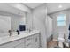 Bright bathroom featuring double sinks, a large mirror, and a shower with modern fixtures at 10836 Montana Blanca Ave, Las Vegas, NV 89166