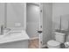 Neutral toned bathroom featuring a sink, toilet, towel rack, and light wood-look floor at 10836 Montana Blanca Ave, Las Vegas, NV 89166