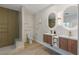 Bathroom with double sink vanity, modern lighting, and a shower with glass shelves at 17 Winding Rd, Henderson, NV 89052