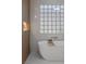 Close-up of a modern bathroom with a soaking tub and unique glass-block window at 17 Winding Rd, Henderson, NV 89052