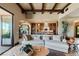 Spacious living room featuring exposed beams, a stone fireplace, and open access to the kitchen at 20 Via Paradiso St, Henderson, NV 89011