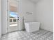 Bright bathroom showcasing a freestanding tub, unique patterned tile flooring, and a door to the outdoors at 21 Sawgrass Ct, Las Vegas, NV 89113