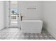 Bright bathroom showcasing a freestanding tub, unique patterned tile flooring, and a door to the outdoors at 21 Sawgrass Ct, Las Vegas, NV 89113