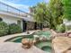 Lush backyard with a custom pool and spa area featuring natural rock accents and mature landscaping at 21 Sawgrass Ct, Las Vegas, NV 89113