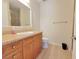 Well-lit bathroom featuring wood cabinets with granite countertops, shower and white toilet at 21 Via Visione # 206, Henderson, NV 89011