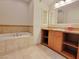 Bathroom featuring a tub with tile surround and vanity with tile countertop and cabinet storage at 21 Via Visione # 206, Henderson, NV 89011
