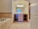 Bathroom featuring a tub with tile surround, vanity with tile countertop, and cabinet storage at 21 Via Visione # 206, Henderson, NV 89011