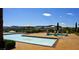 Inviting pool and hot tub area with umbrellas, decorative statues, and beautiful mountain views in the background at 21 Via Visione # 206, Henderson, NV 89011
