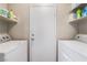 Functional laundry area with white washer, dryer, and shelving for supplies at 2307 Tuscarora Ct, Las Vegas, NV 89142