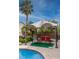Relaxing backyard seating area with a swing under a pergola, surrounded by lush landscaping and a sparkling pool at 2383 Thayer Ave, Henderson, NV 89074