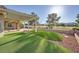 Backyard featuring synthetic grass, rock landscaping, covered patio, and golf course views at 2829 Golf Links Dr, Las Vegas, NV 89134