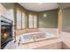 Beautiful bathroom featuring a large tub, tiled surround, fireplace, and shuttered windows at 3004 Astoria Pines Cir, Las Vegas, NV 89107