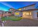 This backyard offers a putting green, covered patio, and manicured landscaping at dusk at 3213 Molinos Dr, Las Vegas, NV 89141